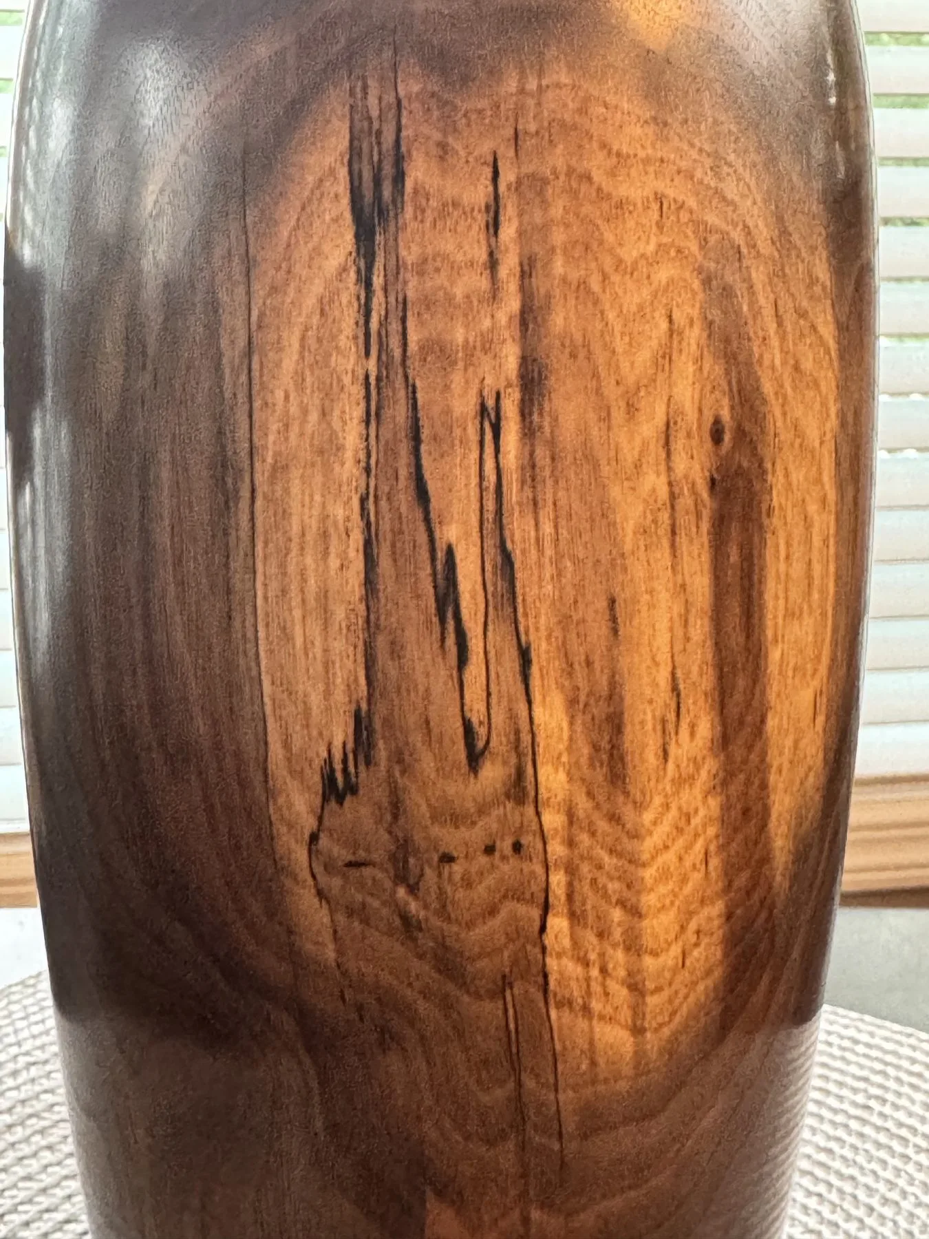 Close-up of golden brown walnut grain with dark natural streaks on the vase
