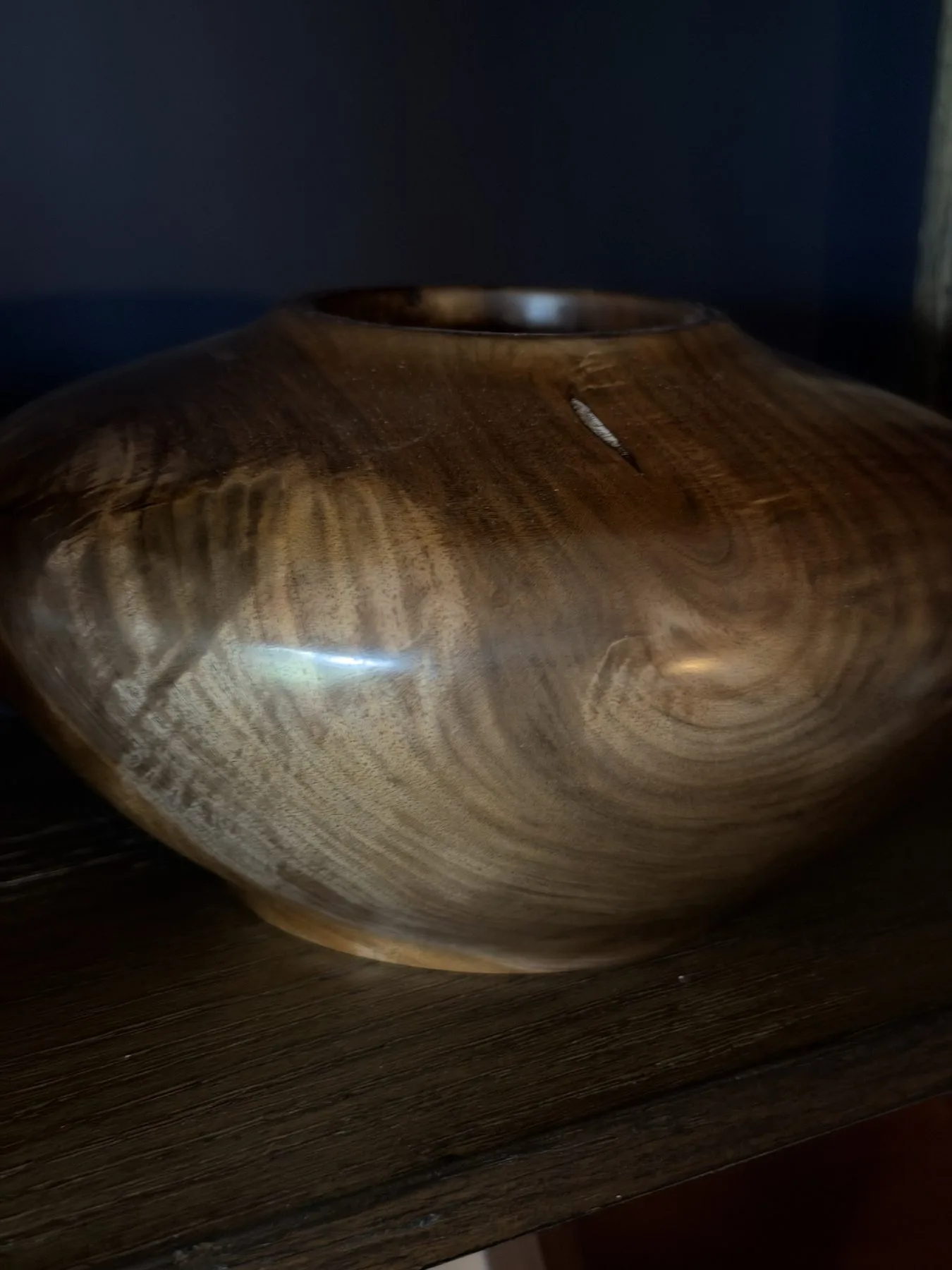 Close view of curved walnut grain below the small opening of the hollow form