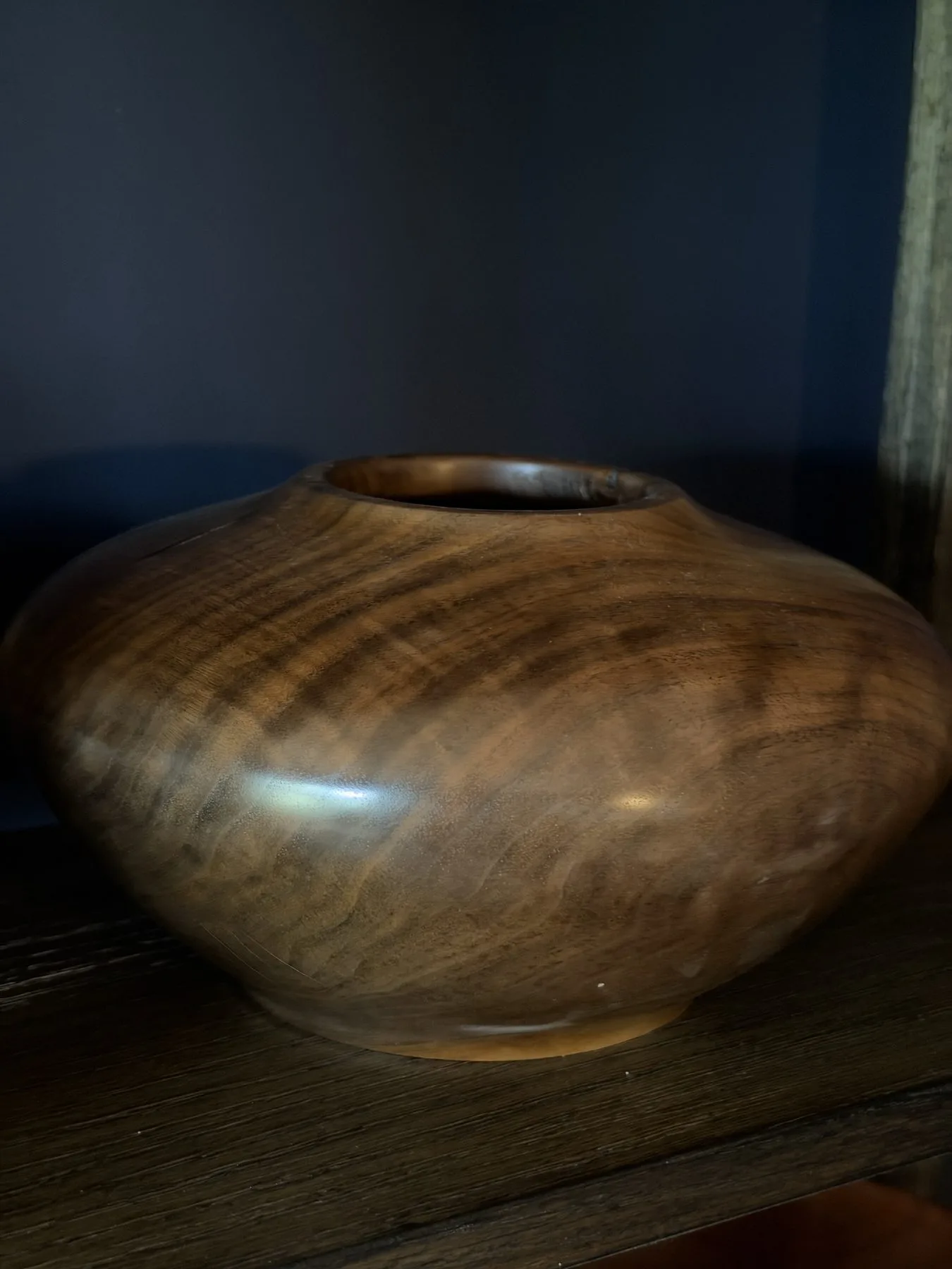 Opposite side of the walnut hollow form with sweeping brown grain across the shoulder and a narrow base