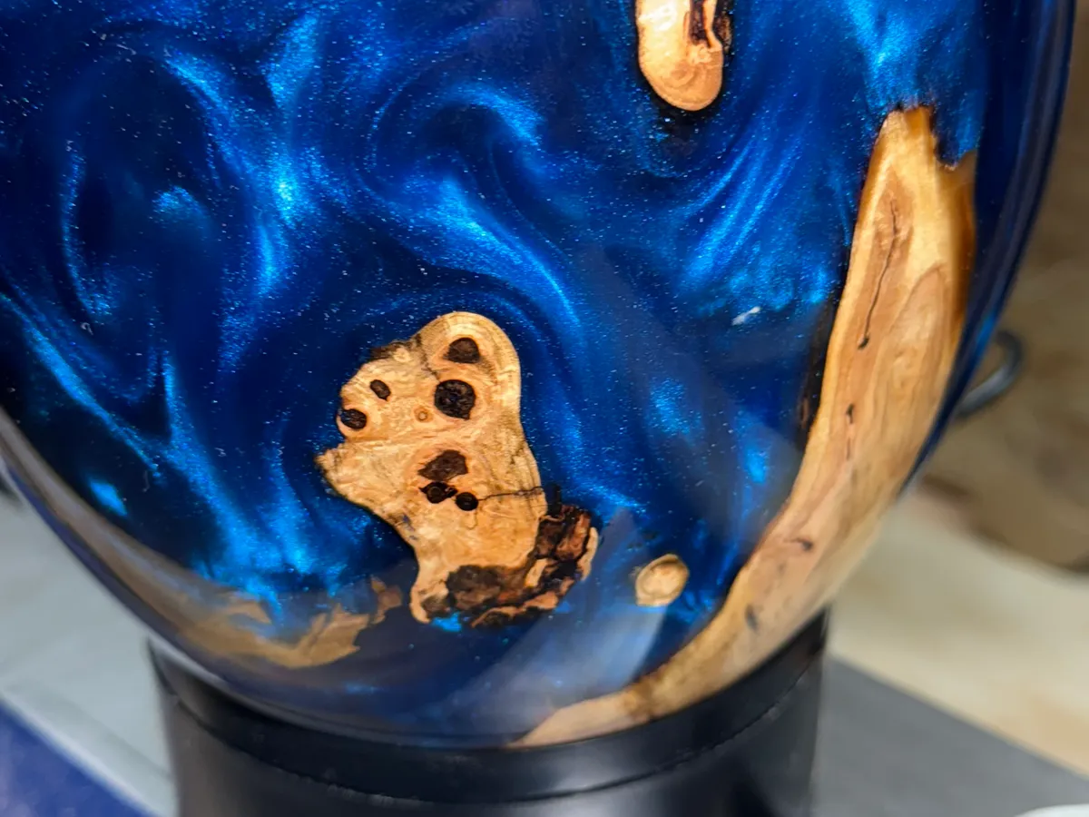 Close view of electric blue resin wrapping around natural apple wood inclusions