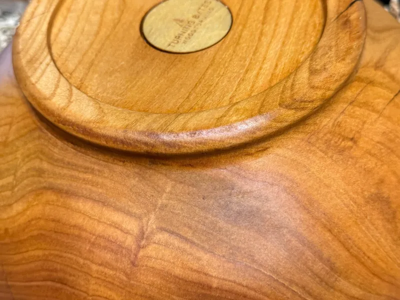 Bottom of a hand-turned cherry bowl showing the foot and Turning Bytes maker's mark