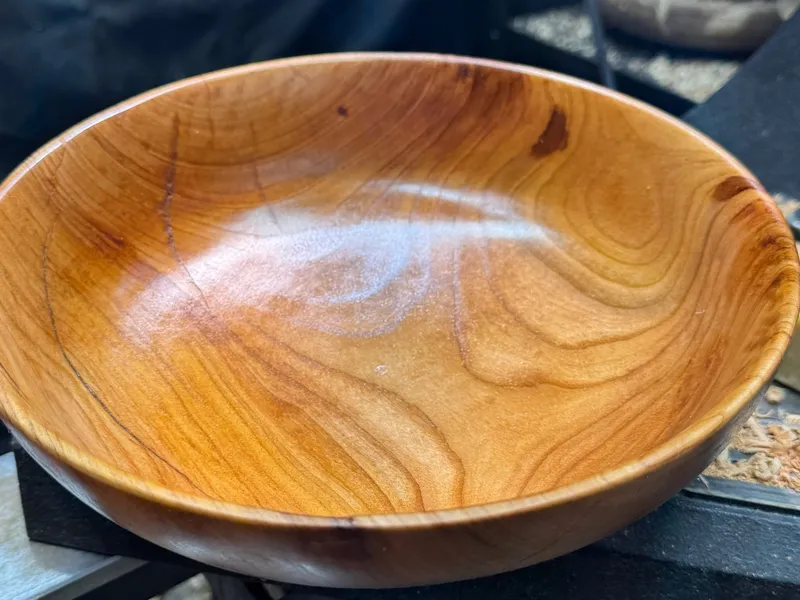 Hand-turned cherry bowl fresh off the lathe, showing the pale pinkish-brown color that deepens over time