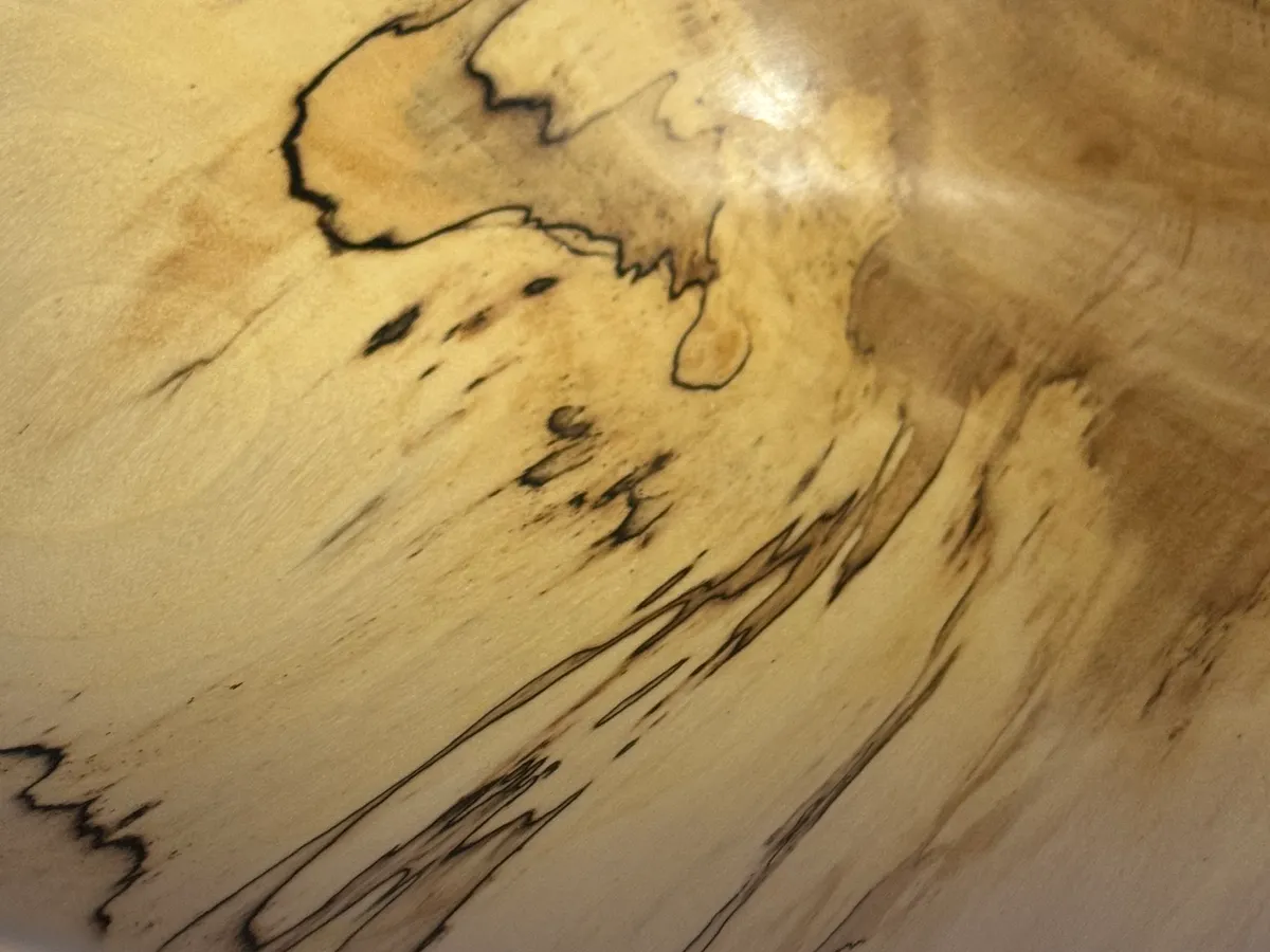 Close-up detail of spalted maple bowl showing dramatic black zone lines and fungal figure in pale wood