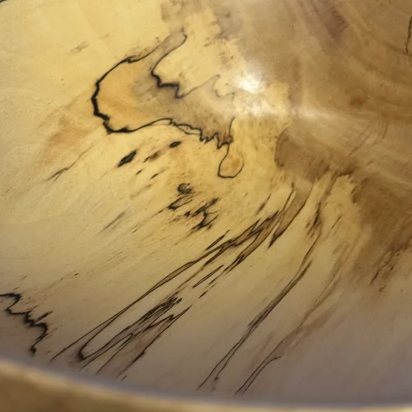 Close-up detail of spalted maple bowl showing dramatic black zone lines and fungal figure in pale wood