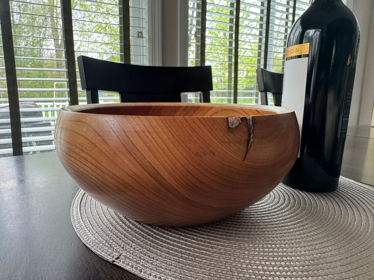 Cherry wood bowl on a dining table with warm grain and a small natural rim check
