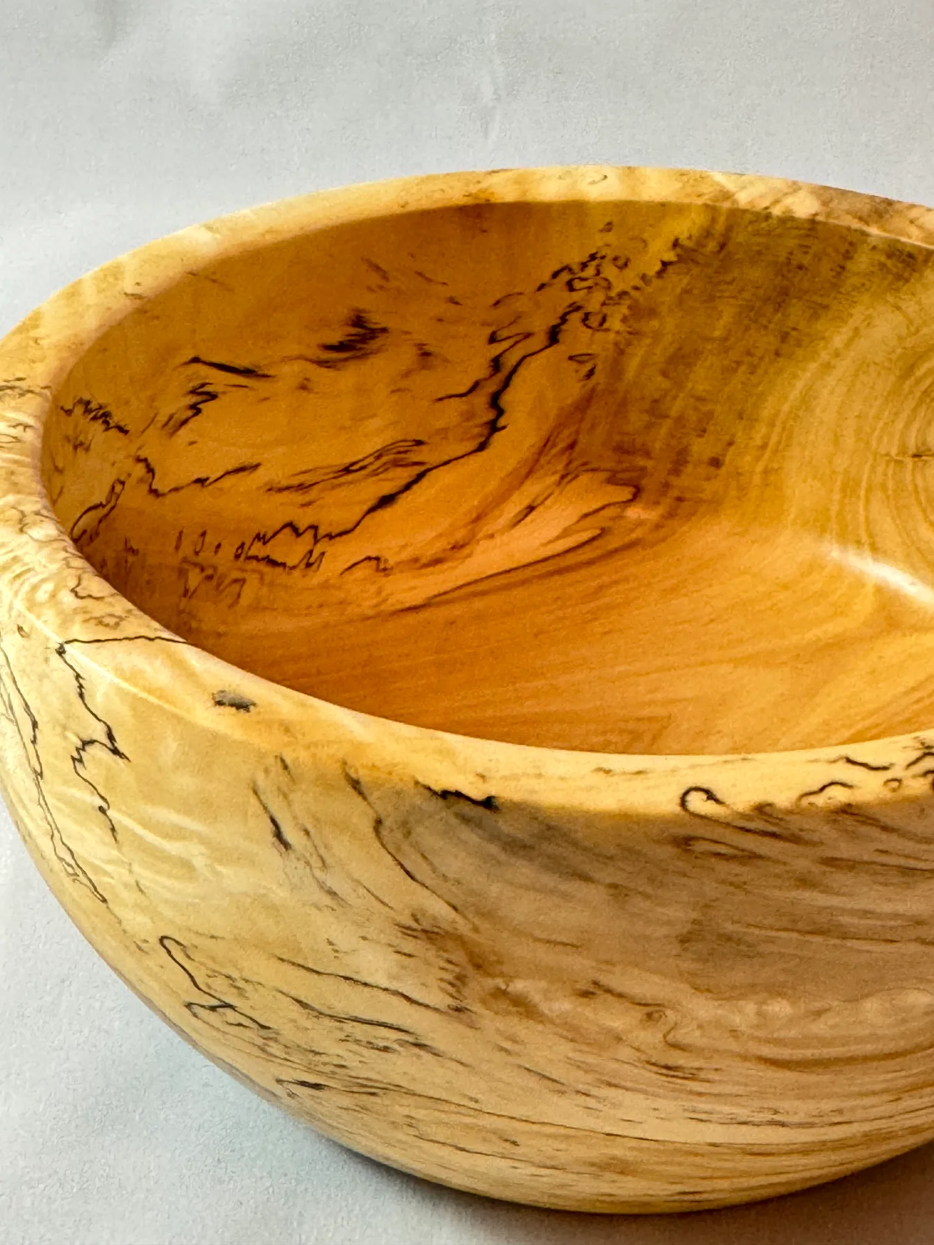 Side view of a smaller spalted maple bowl showing pale maple and black fungal figure