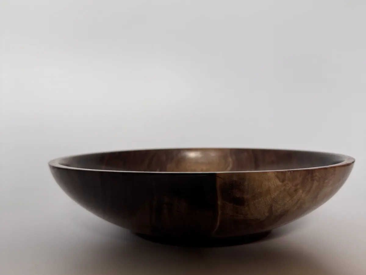 Side profile of hand-turned black walnut bowl with a low open table form