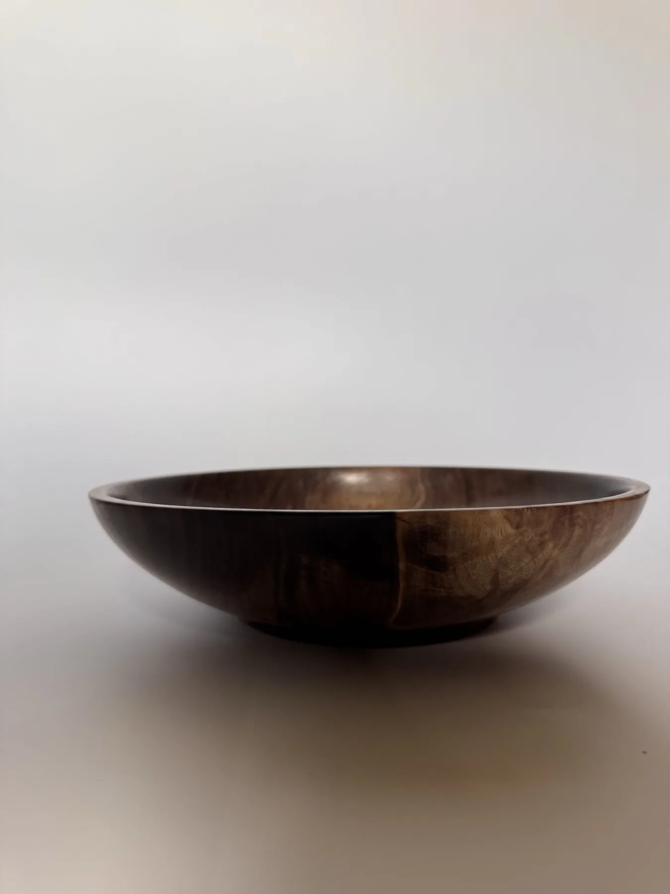 Side profile of hand-turned black walnut bowl with a low open table form