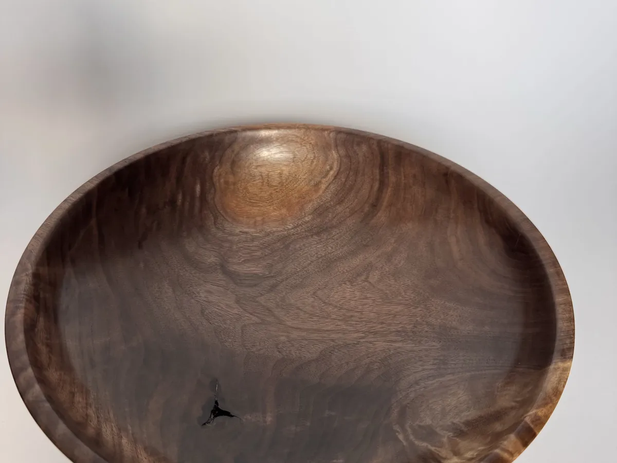 Interior view of low black walnut bowl showing dark grain, lighter figure, and a small natural inclusion