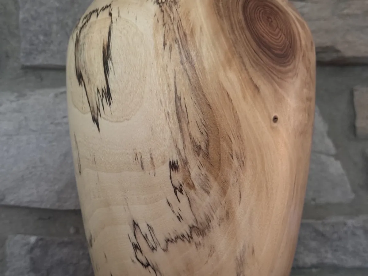 Angled view of pale maple vase with spalting lines and a darker knot near the shoulder