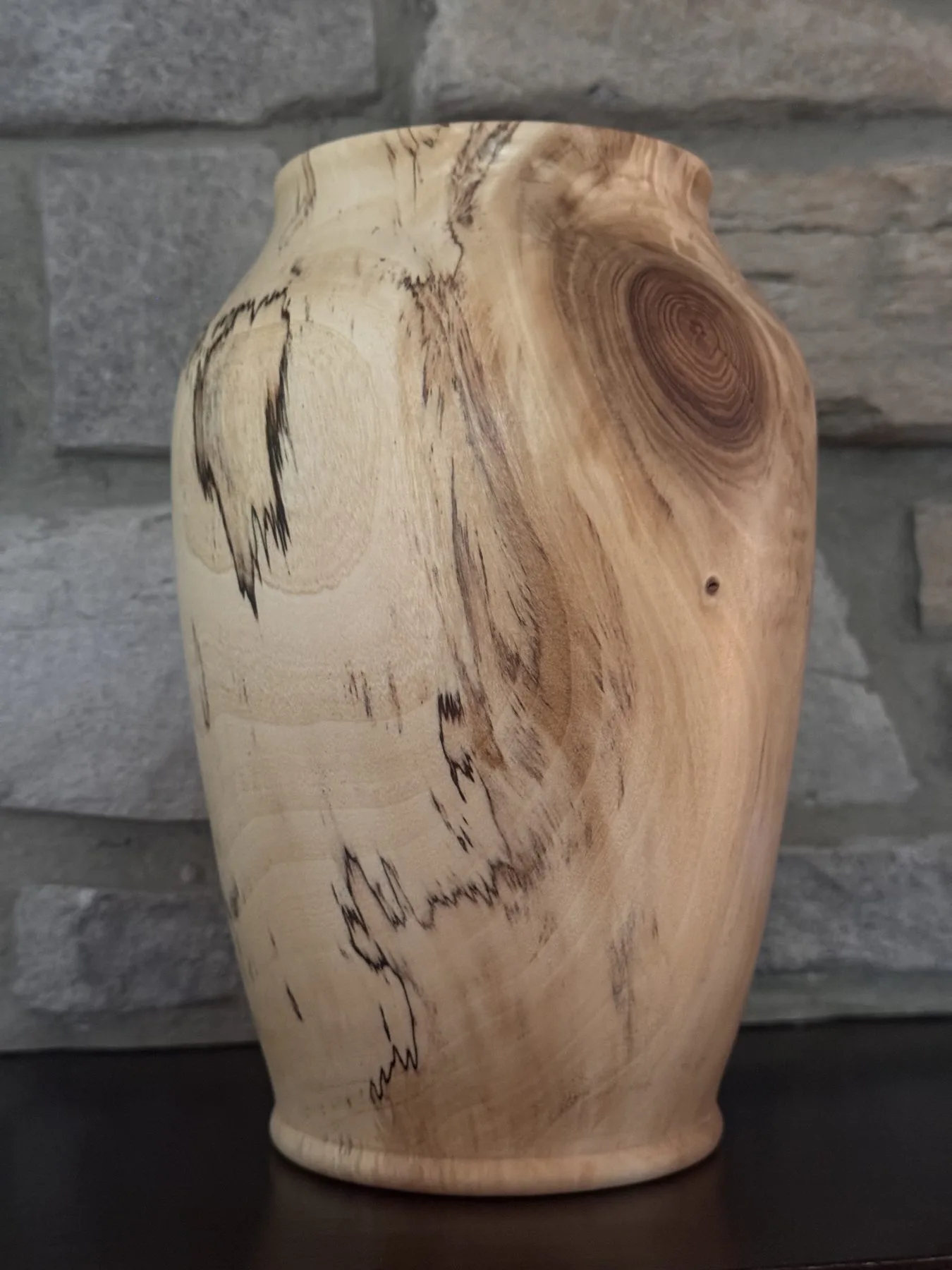 Angled view of pale maple vase with spalting lines and a darker knot near the shoulder