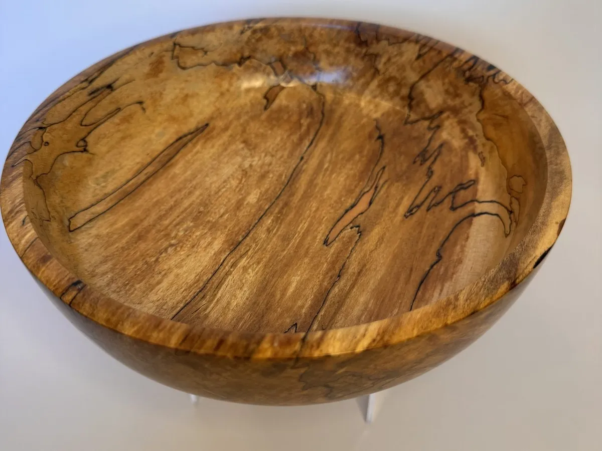 Top view of spalted maple bowl with amber grain, black zone lines, and light interior