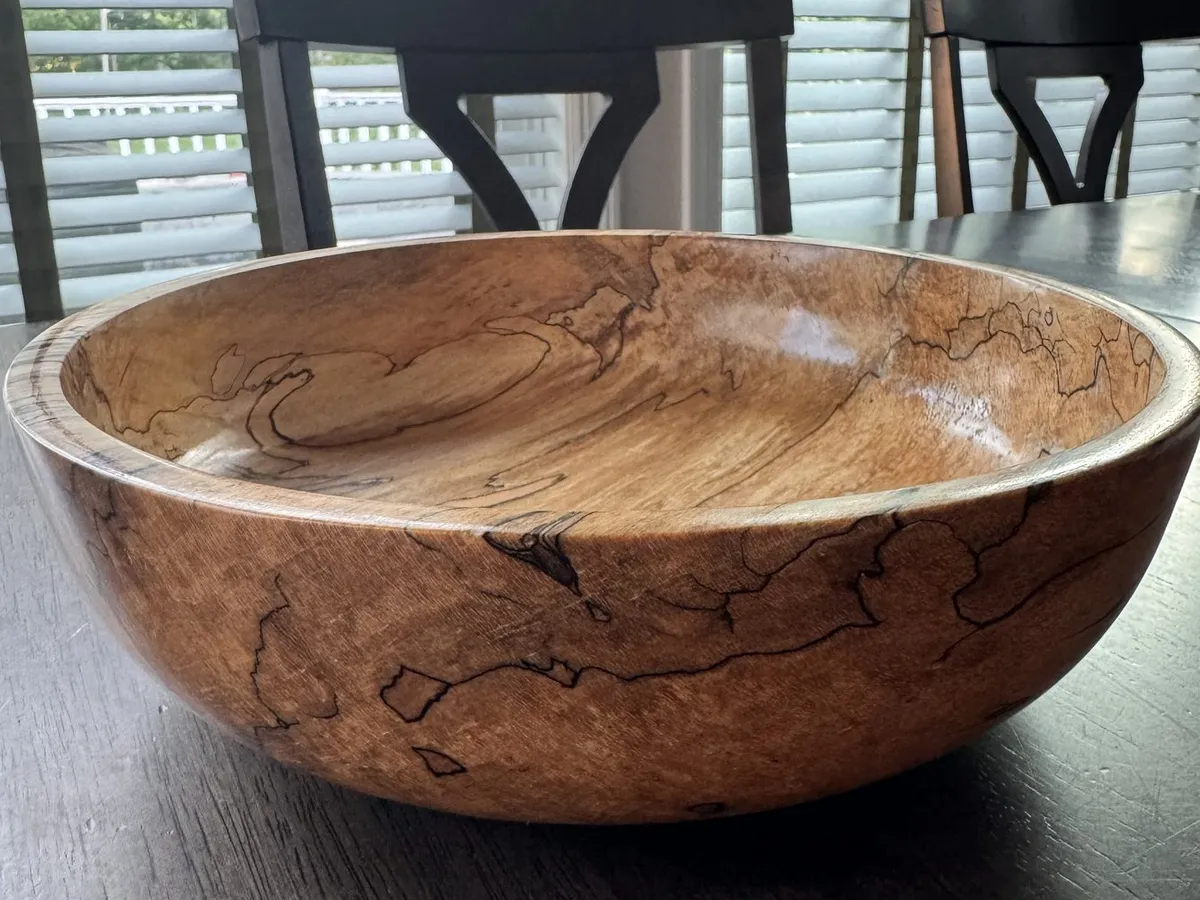 Spalted maple bowl displayed on a table with dark figured outer wall