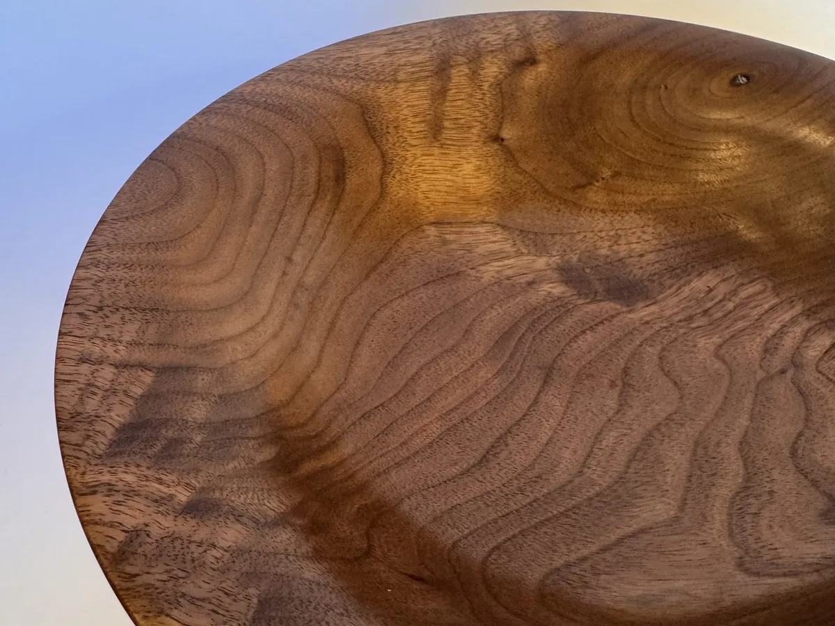 Interior detail of walnut bowl showing feathered grain and warm shellac wax finish