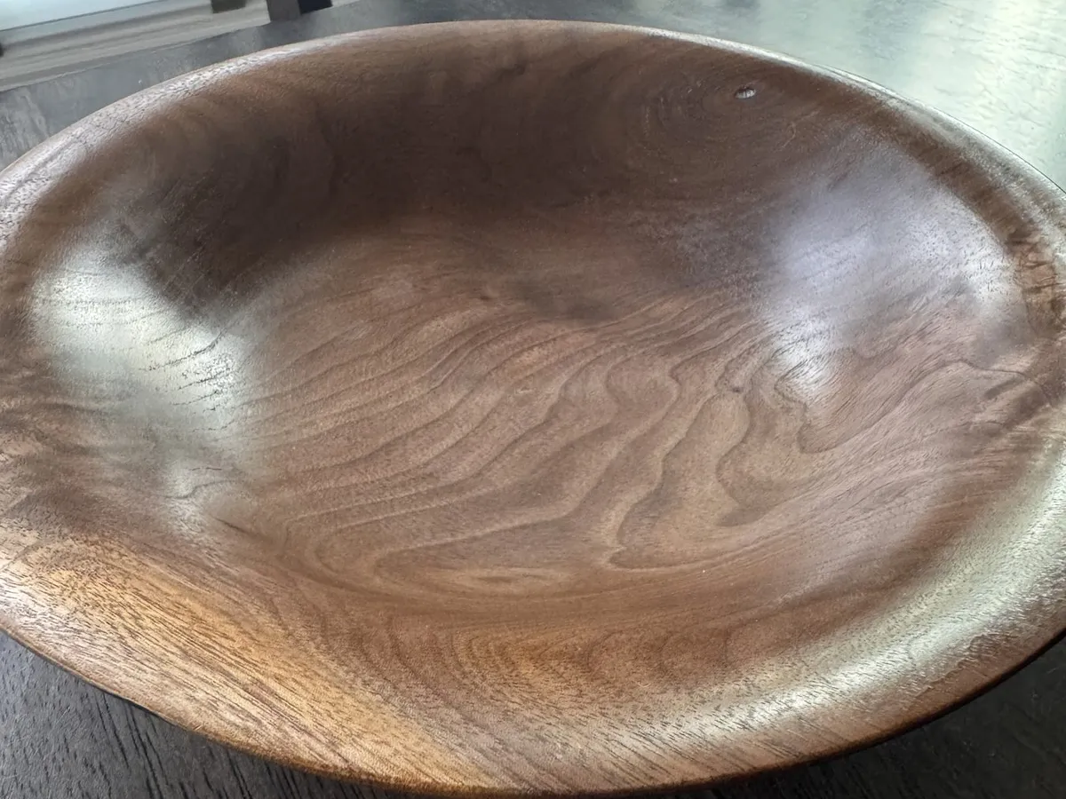 Angled tabletop view of shallow walnut bowl with broad lip and polished surface