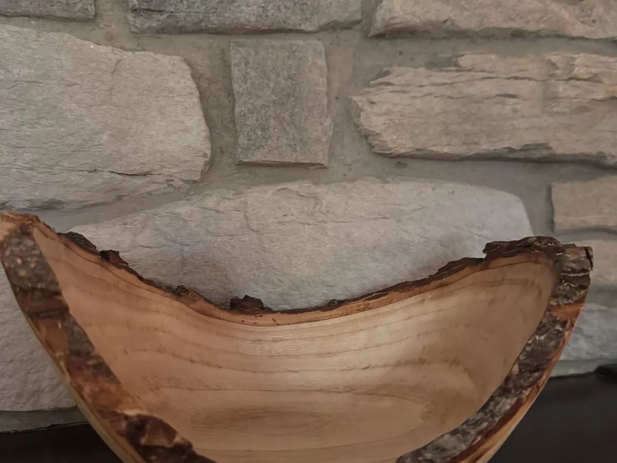 Craggy winged maple bowl displayed on a mantel against a stone background