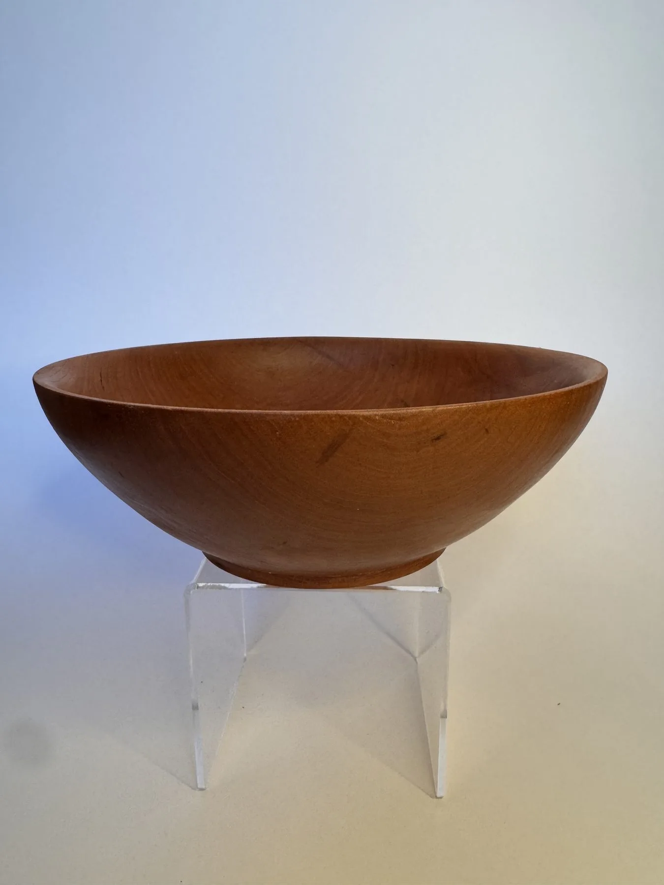 Side profile of simple hand-turned cherry bowl with small raised foot