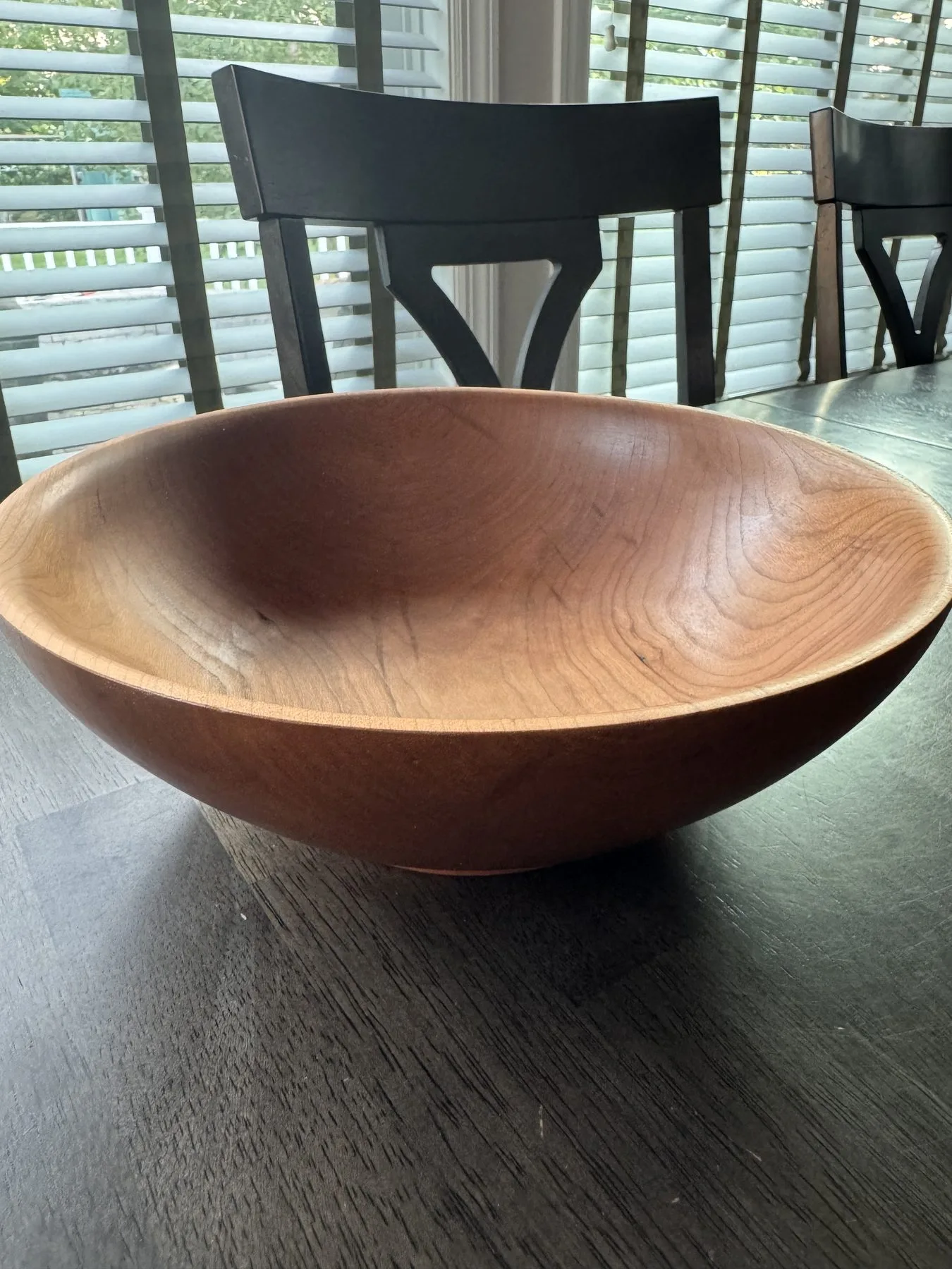 Medium cherry bowl displayed on a table with warm reddish brown grain