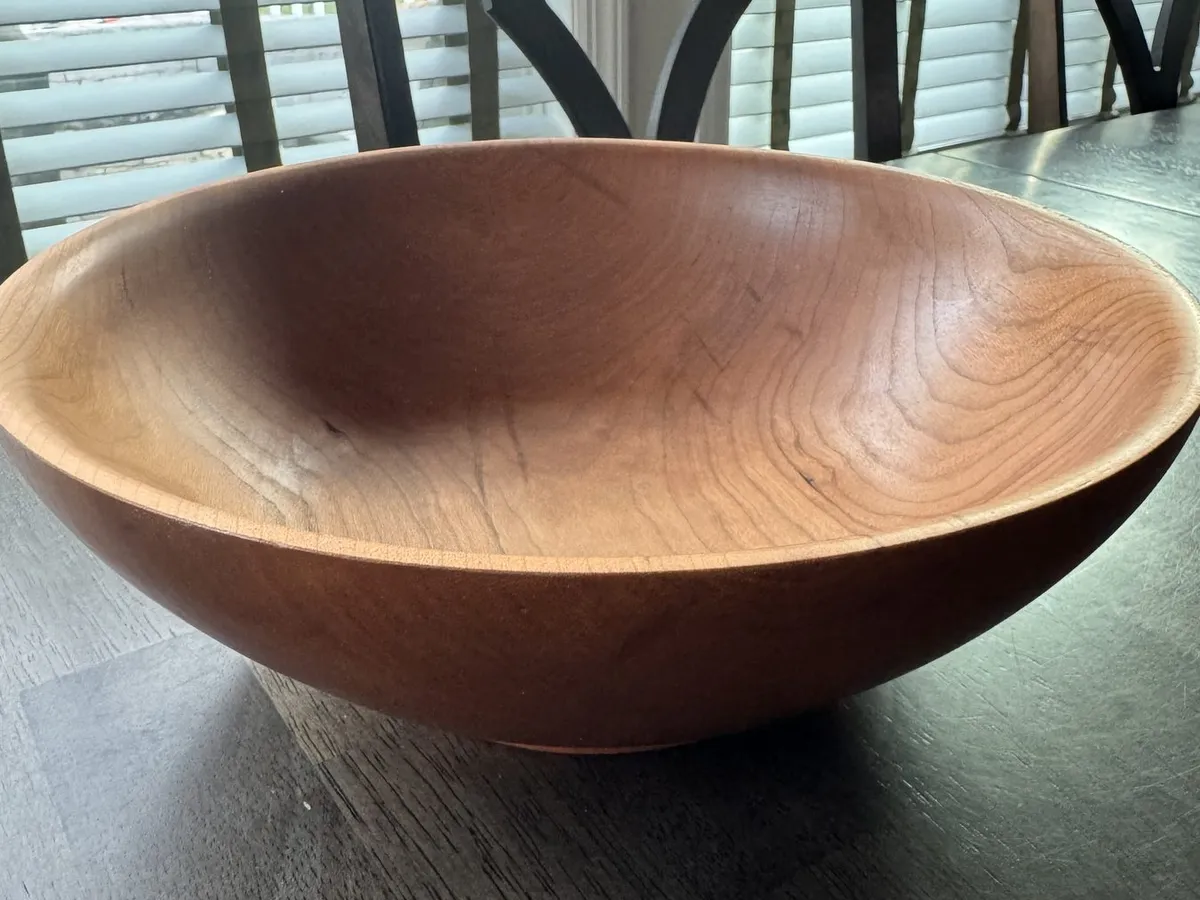 Medium cherry bowl displayed on a table with warm reddish brown grain