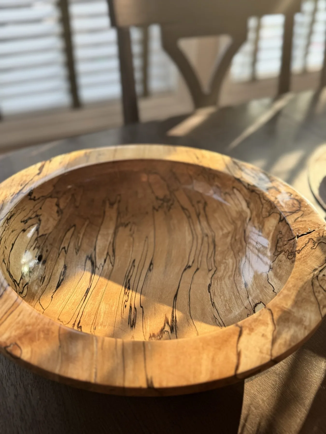 14-inch spalted maple bowl illuminated by warm indoor sunlight on a dining table