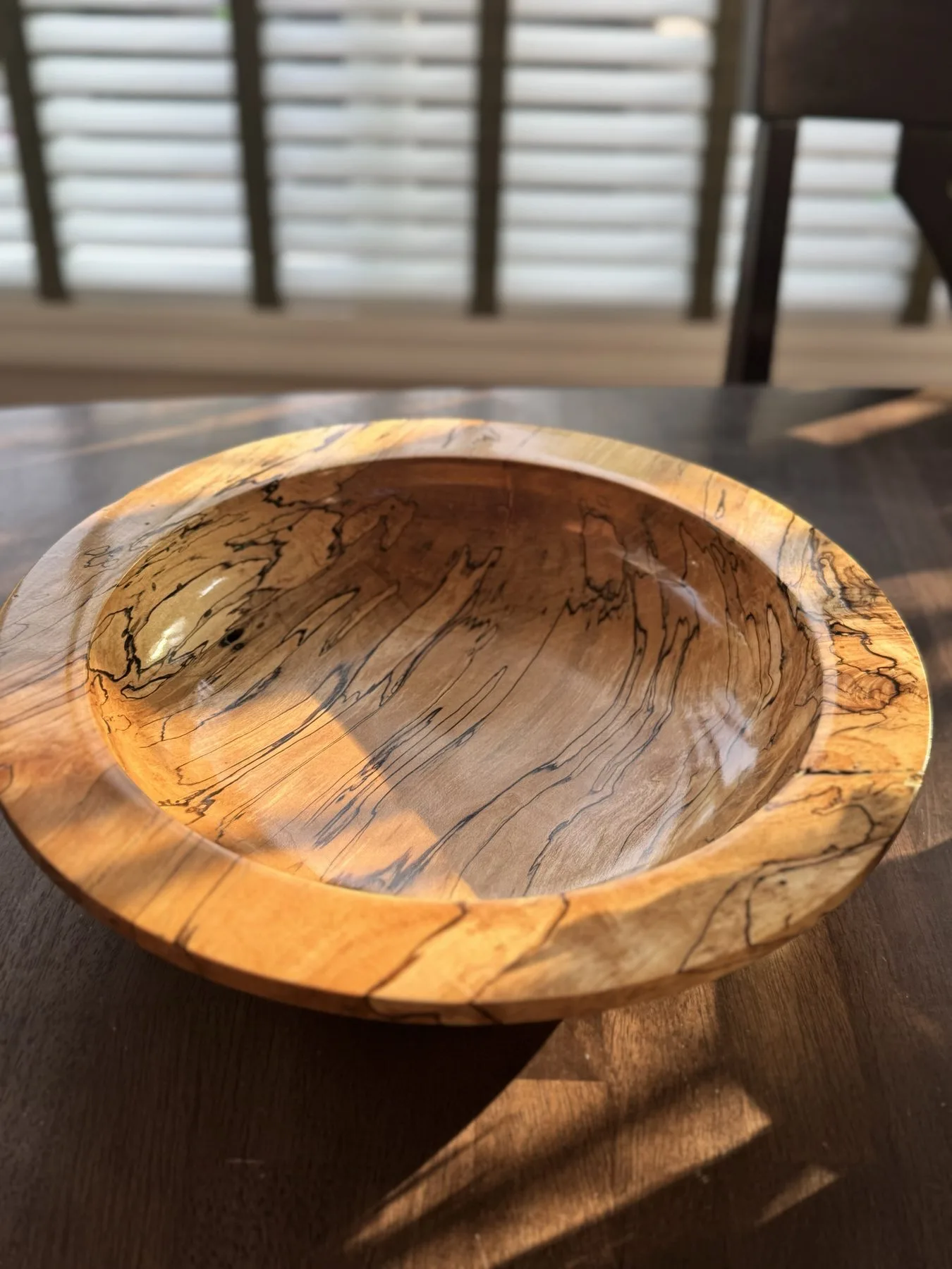 Angled view of 14-inch spalted maple bowl showing wide flat rim and smooth interior basin