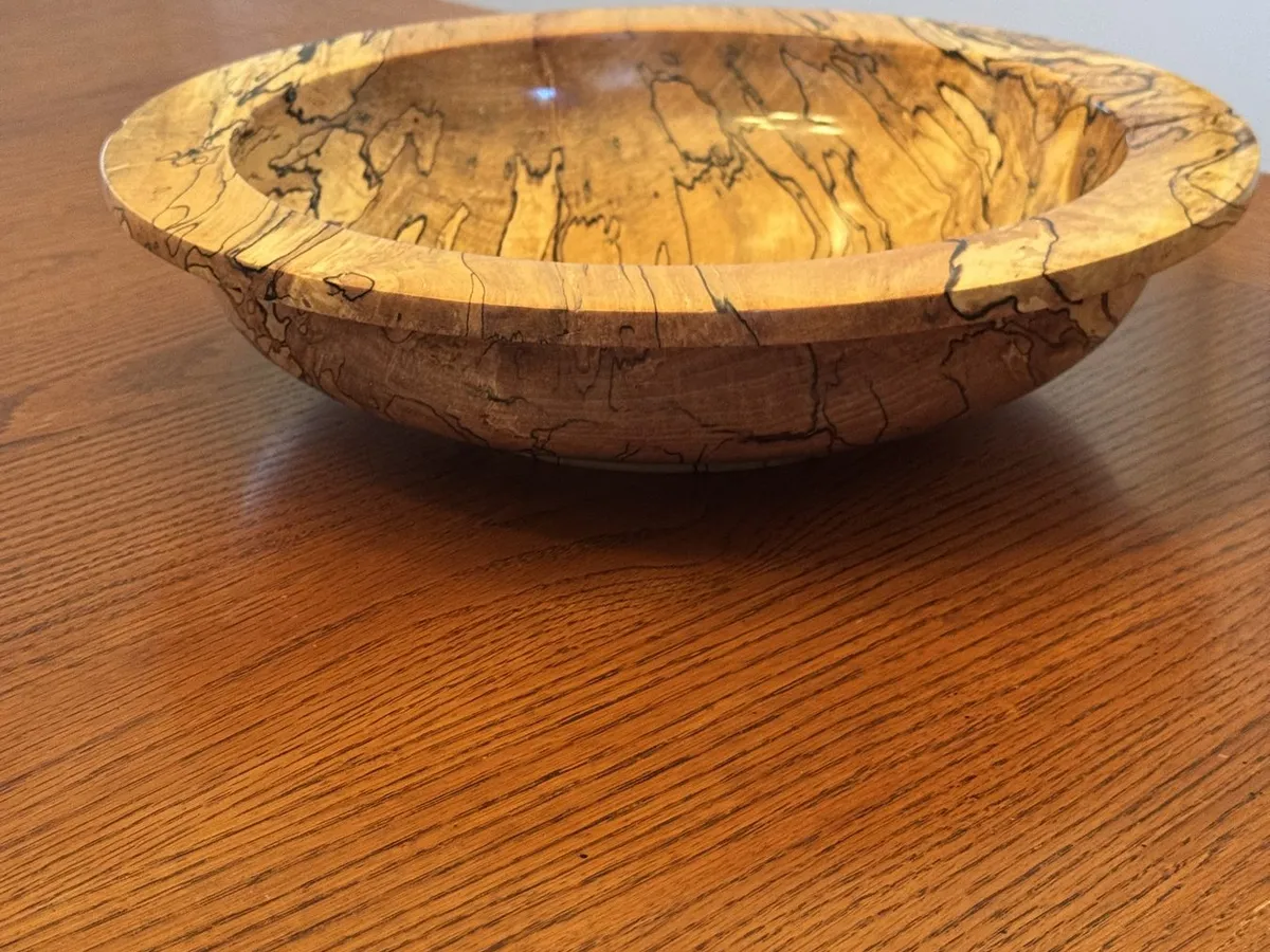 Side profile view of wide-rim 14-inch spalted maple bowl on wood tabletop