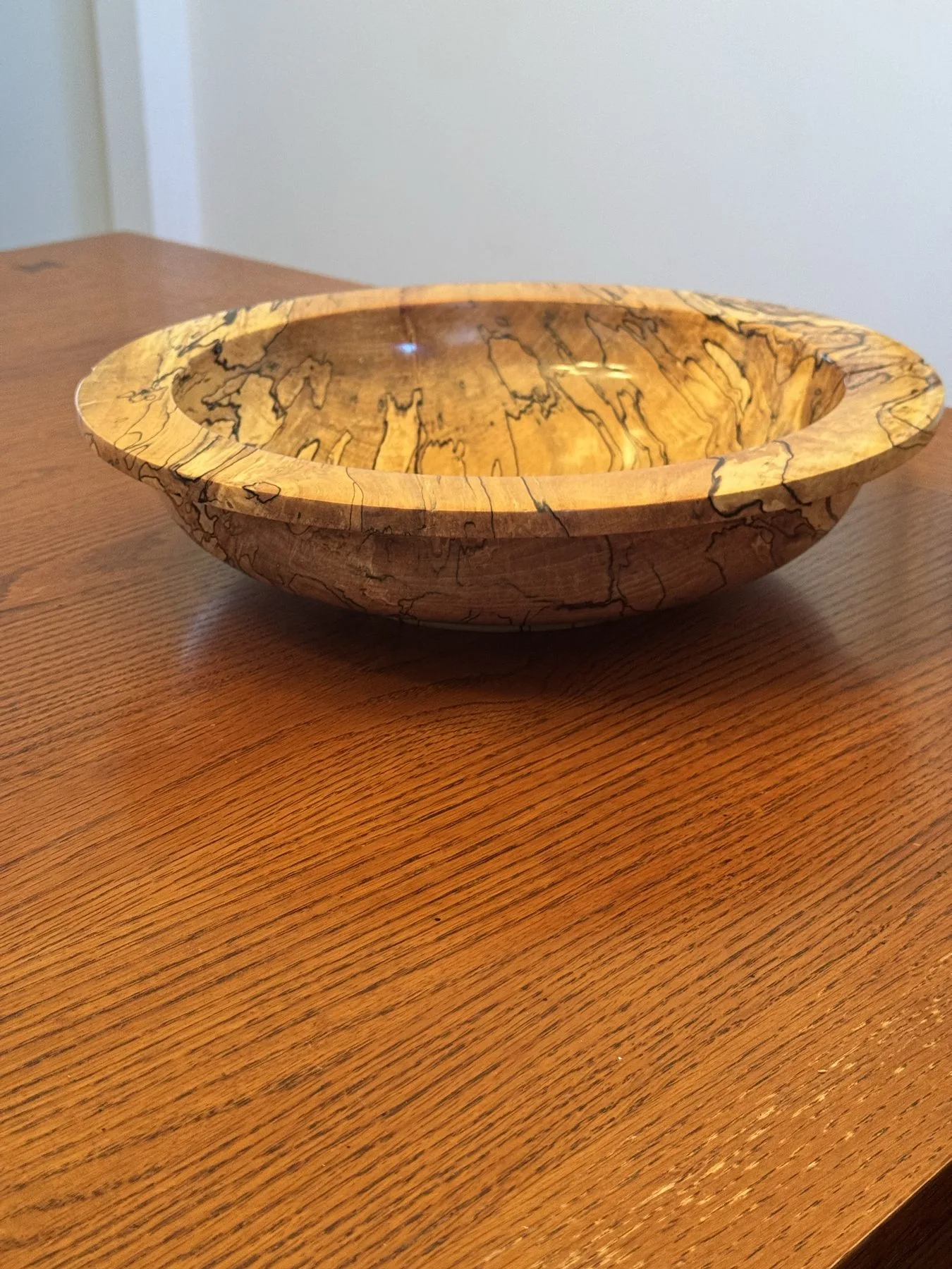 Side profile view of wide-rim 14-inch spalted maple bowl on wood tabletop