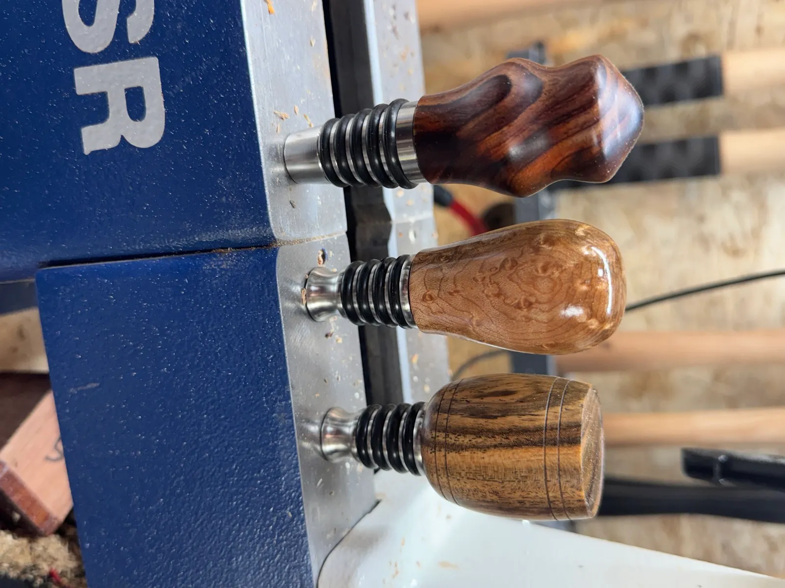 Three hand-turned bottle stoppers showing walnut, maple burl, and spalted maple